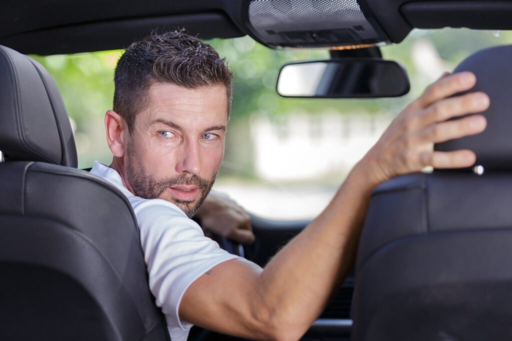 driver turning in his seat to look behind to reverse